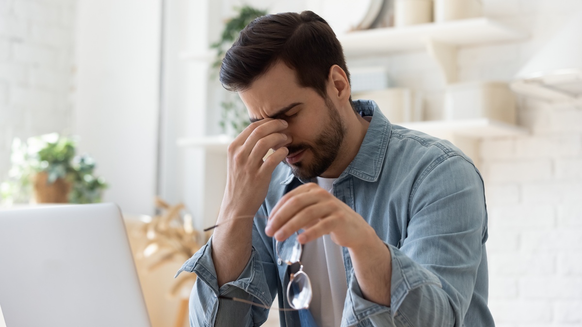 man taking off glasses and massaging the bridge of his nose