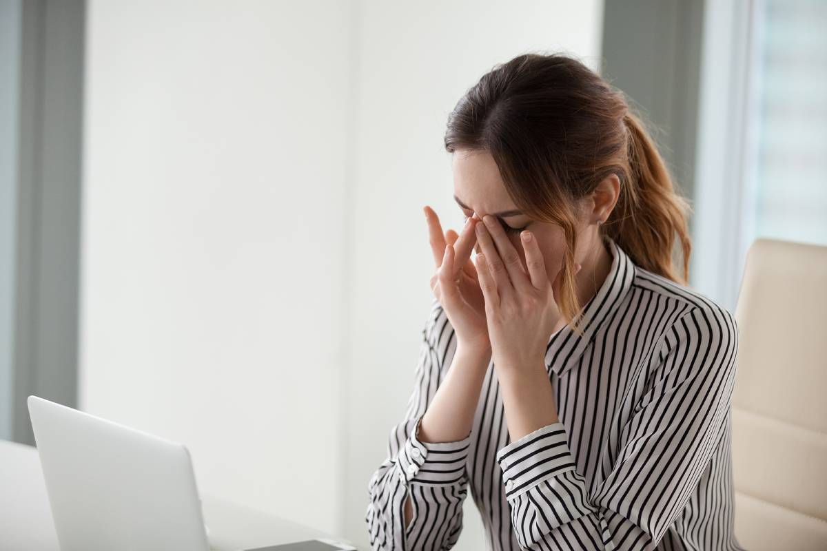 tired woman massaging the bridge of her nose at work